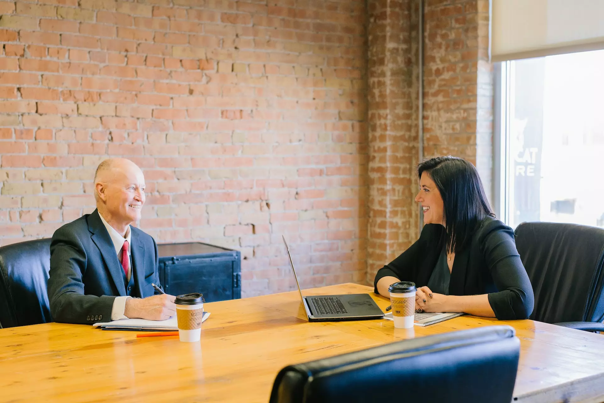 Two people conversing over coffees at a conference table
