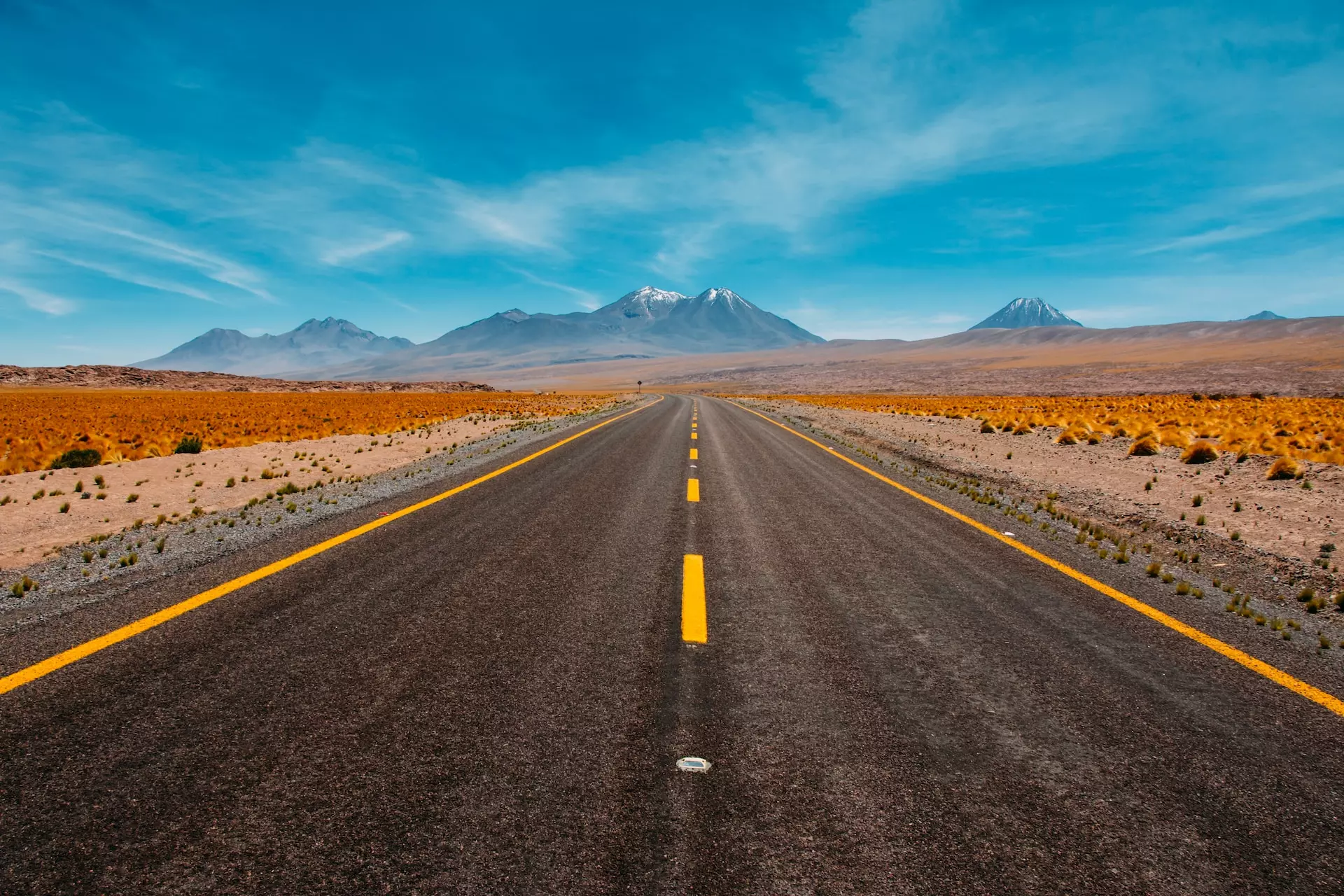 An empty highway leading towards distant mountains
