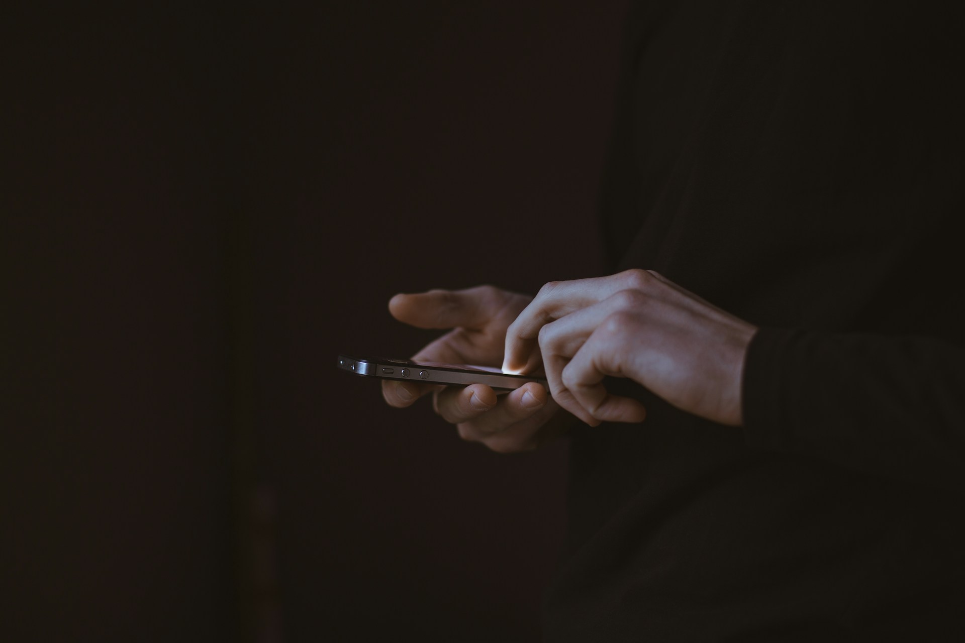 Silhouette of a person's hands using a smart phone